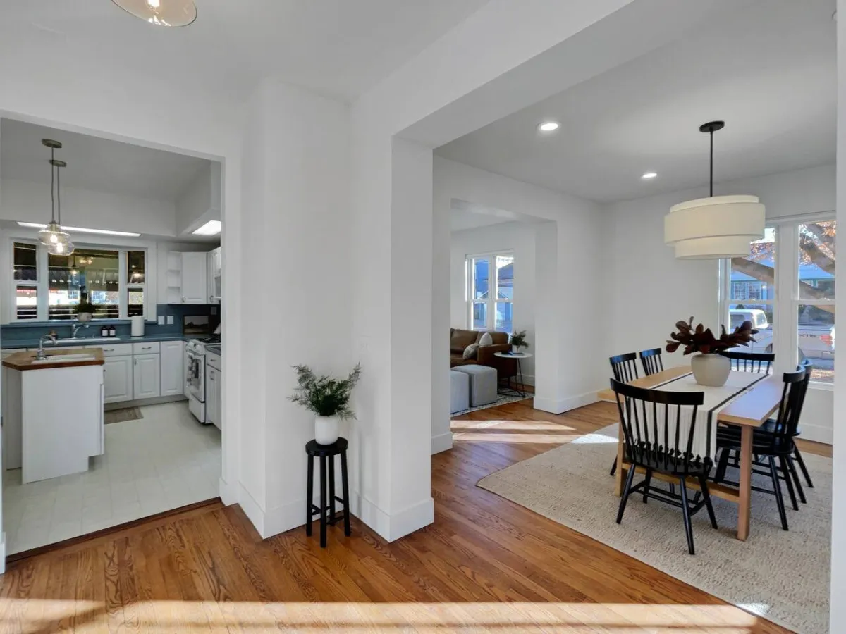 This image provides a view that connects the dining table, kitchen area, and living room. The dining table is large and inviting, with a clear line of sight to the kitchen and relaxed living area, emphasizing togetherness and connectivity.