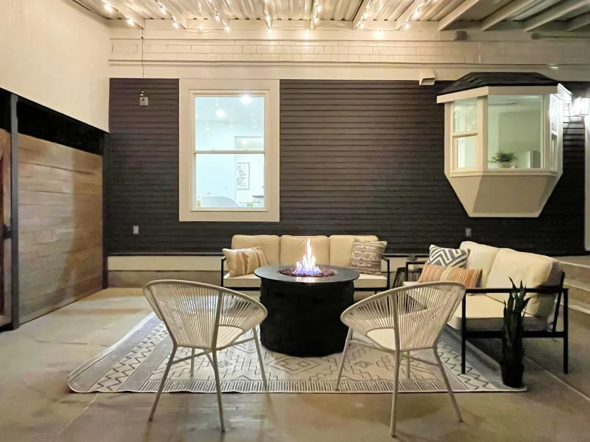An outdoor fire pit setup featuring comfortable seating and warm string lights, creating an inviting space for evening gatherings. The arrangement is designed for guests to relax, socialize, and enjoy the ambiance of a private outdoor retreat after a day of exploration.