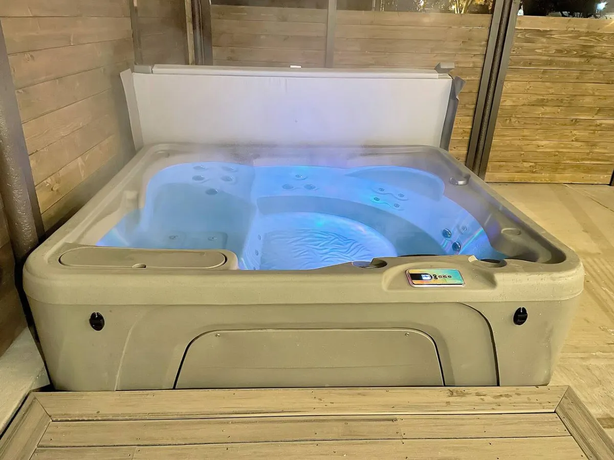 A steaming hot tub illuminated by LED lights offers a soothing retreat after a day of adventure. The inviting atmosphere suggests comfort and relaxation, perfect for unwinding and sharing stories with friends or family.