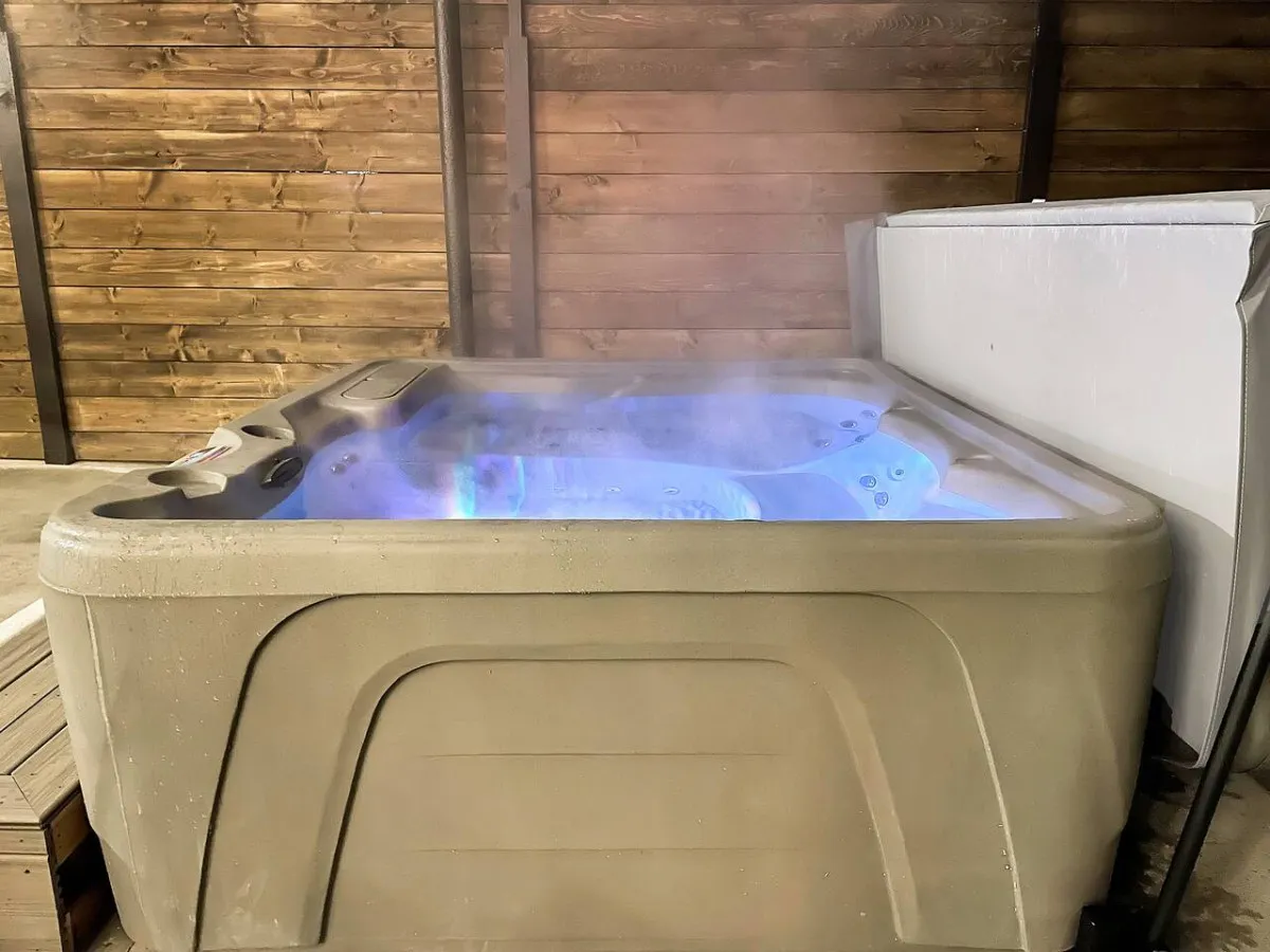 A private indoor hot tub surrounded by wooden walls, with steam rising and a calming, spa-like atmosphere. The setting is tranquil and designed for immersive relaxation and socializing, offering a perfect wind-down after outdoor adventures.