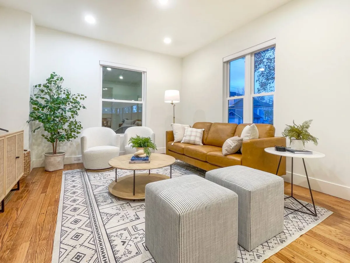 A welcoming space centered around a leather sofa and coffee table stacked with books, flanked by striped ottomans and a lush green plant. The setting exudes comfort and is ideal for casual conversations, reading, or enjoying time with loved ones.