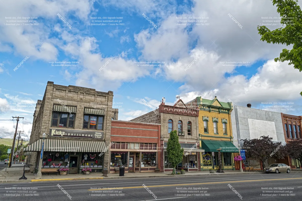 A lively street view featuring the 'Kicks' sportswear storefront with colorful architecture, leafy trees, and flower pots lining the sidewalk. The inviting scene suggests easy pedestrian access to local shops and hints at a bustling, walkable neighborhood atmosphere.